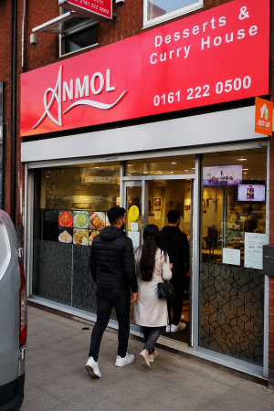 Anmol Sweet House desserts and curry house storefront with customers entering